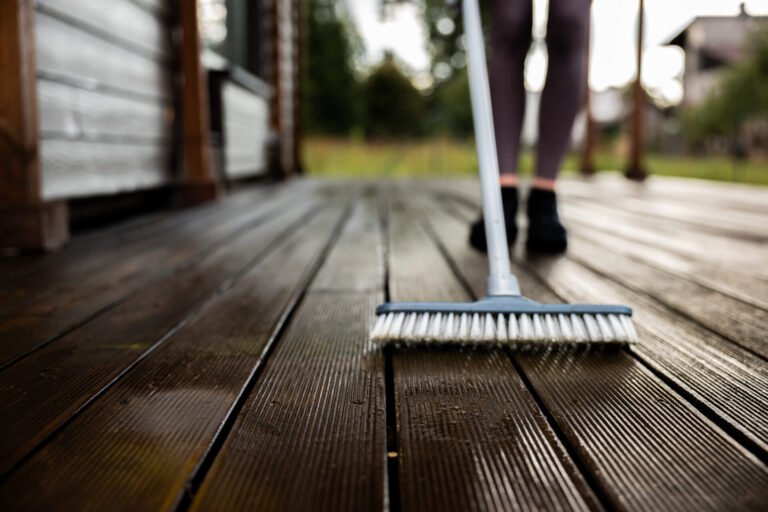 Woman washes a wooden terrace before painting it in her modern private house